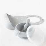 Bumkins Silicone First Feeding Set: Gray sits in front of a gray silicone bib on a white background.