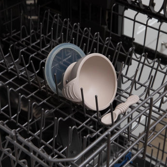 Bumkins Silicone First Feeding Set: Sand sits in the top rack of an open dishwasher.