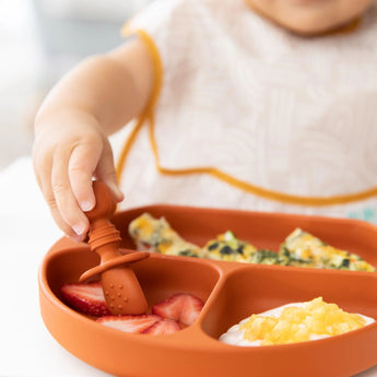 Close-up of a child enjoying strawberries, omelette, and yogurt from Bumkins Silicone Grip Dish: Clay with matching toddler utensils.