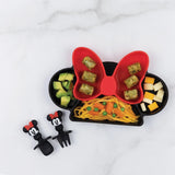 Bumkins Silicone Grip Dish: Minnie Mouse with pasta, peas, avocado & cheese sits near matching utensils on a marble background.