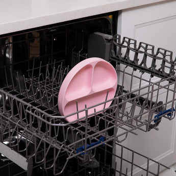 Bumkins Silicone Grip Dish: Pink sits in the top rack of an open dishwasher.