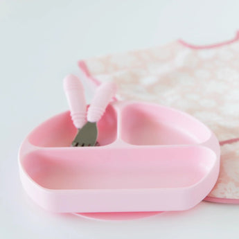 Bumkins Silicone Grip Dish: Pink holds matching utensils next to a pink floral bib on a white background.
