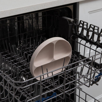 Bumkins Silicone Grip Dish: Sand sits in the top rack of an open dishwasher.