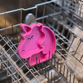 Bumkins Silicone Grip Dish Special Edition: Unicorn sits in the top rack of an open dishwasher.