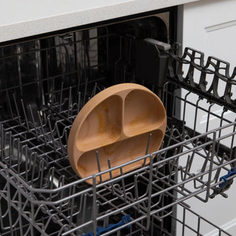 Bumkins Silicone Grip Dish: Wood Grain sits in the top rack of an open dishwasher.