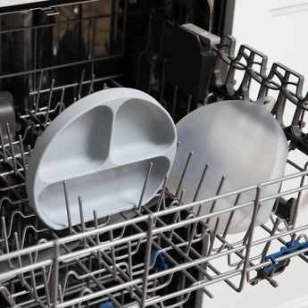 Bumkins Silicone Grip Dish with Lid (3 Section): Gray sits in the top rack of an open dishwasher.