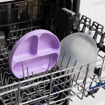 Bumkins Silicone Grip Dish with Lid (3 Section): Lavender sits in the top rack of an open dishwasher.