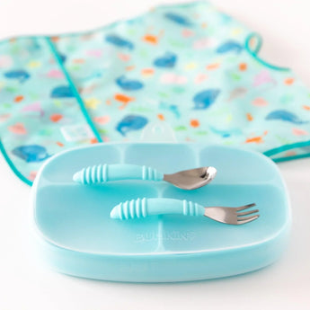 Bumkins Silicone Grip Dish with Lid (5 Section): Blue sits on a white background with utensils on top and a blue bib in the background.