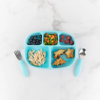 Bumkins Silicone Grip Dish with Lid (5 Section): Blue holds berries, veggies, dino nuggets, & chicken on a marble surface near blue utensils.