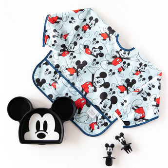 A sleeved bib, Mickey-shaped dish, and utensils from Bumkins Disney Little Ones Gift Bundle: Mickey Mouse Classic on a white background.