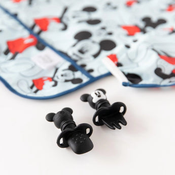 Close-up of Mickey Mouse utensils and a sleeved bib from Bumkins Disney Little Ones Gift Bundle: Mickey Mouse Classic on a white background.