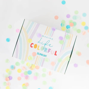 A colorful gift box for Bumkins Ultimate Gift Set - Jungle & Animal Prints surrounded by confetti on a white background.