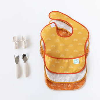 A set of 3 bibs and two sets of beige utensils from Bumkins Ultimate Gift Bundle, Desert Boho on a white background.
