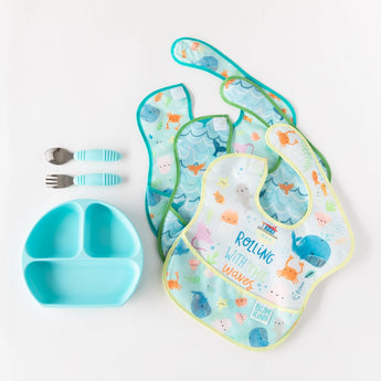 Three ocean-themed bibs, a blue plate, and blue utensils from Bumkins Ultimate Gift Set - Ocean Life & Whale Tail on a white background.