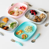 Four colorful plates, including Bumkins Silicone Grip Tray: Blue, with assorted healthy foods for kids and utensils on a white background.