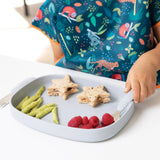 Close-up of a child eating star-shaped sandwiches, snacks, & berries from a Bumkins Silicone Grip Tray: Gray at a white table.