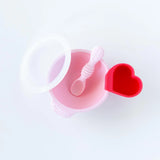 A red Bumkins Silicone Little Dipper 3-Pack: Tutti-Frutti attached to a pink bowl with a matching spoon and clear lid on a white background.