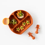 A plate with fruit, veggies, and hummus on a white background, with utensils and an orange Bumkins Silicone Little Dipper 3-Pack: Tutti-Frutti.