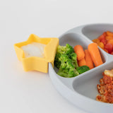 Close-up of a gray plate with veggies and a yellow Bumkins Silicone Little Dipper 3-Pack: Tutti-Frutti with dip on a white background.
