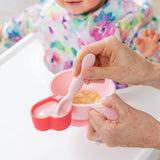 An adult uses spoon to feed a baby in a high chair from a red Bumkins Silicone Little Dipper 3-Pack: Tutti-Frutti.