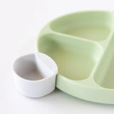Close-up of a marble Bumkins Silicone Little Dipper Round 3-Pack: Taffy attached to a green sectioned plate on a white background.