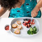 A child enjoys corn dog pieces, fruits, and broccoli, with ketchup in a marble Bumkins Silicone Little Dipper Round 3-Pack: Taffy.