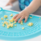 Close-up of a child playing with scrambled eggs on a Bumkins Silicone Sensory Placemat: Blue.