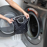 A person holds a Bumkins SuperBib® 3 Pack: Love, Mickey in front of an open front-loading washing machine.