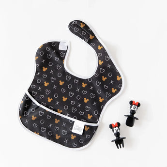 A Bumkins SuperBib® 3 Pack: Love, Minnie lays next to Minnie Mouse-shaped silicone utensils on a white background.