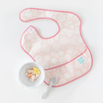 A pink Bumkins SuperBib® 3 Pack: Love You Bunches lays next to shrimp and lemon in a bowl and a spoon on a white background.