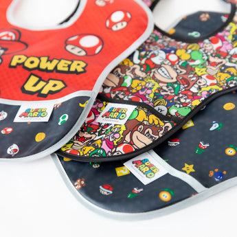 Close-up of Bumkins SuperBib® 3 Pack: Super Mario™ Power-Up fanned out on a white background, with focus on the front pocket.
