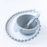 A Bumkins Silicone Accessory Tether 2-Pack: Gray is attached to a gray spoon in a gray bowl on a white background.