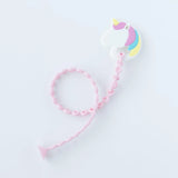 A Bumkins Silicone Accessory Tether 2-Pack: Pink attached to a unicorn-shaped teether on a white background.