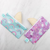 Sandwich halves peek out from Bumkins Reusable Snack Bag, Small 2-Pack: Rainbows & Unicorns on a marble background.