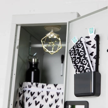 An open locker with a black bottle, geometric decor, and Bumkins Reusable Snack Bag, Small 2-Pack: XOXO & Hearts in a bin on the door.
