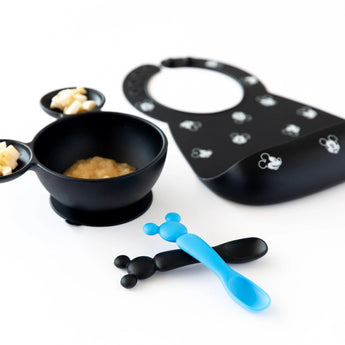 Bumkins Silicone Dipping Spoons: Mickey Mouse (Black and Blue) lay next to a black bowl of food and a black bib on a white background.