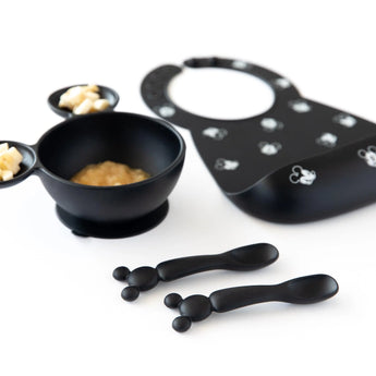 Bumkins Silicone Dipping Spoons: Mickey Mouse (Classic Black) lay in front of a black bowl of food and black bib on a white background.