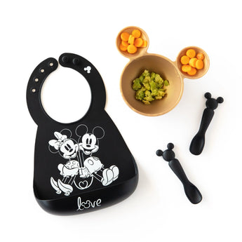 Bumkins Silicone Dipping Spoons: Mickey Mouse (Classic Black) lays next to a black bib and a gold bowl with food on a white background.