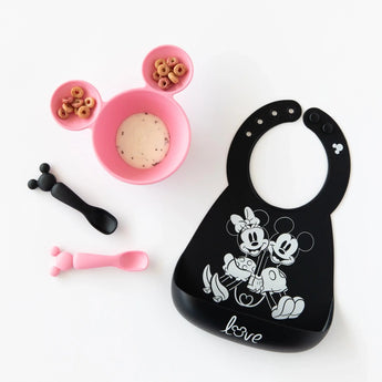 Bumkins Silicone Dipping Spoons: Minnie Mouse (Black and Pink) lay next to a pink bowl with food, and a black bib on a white background.