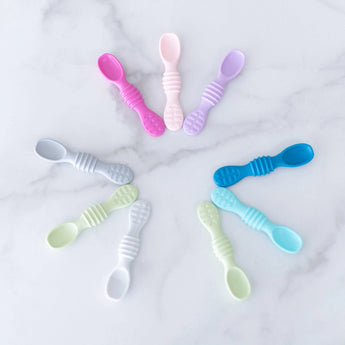 Bumkins Silicone Dipping Spoons 3 Pack: Lollipop is artfully displayed with other spoons on a marble background.