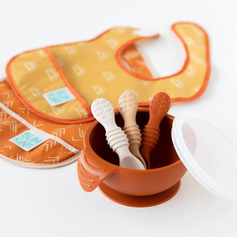 Bumkins Silicone Dipping Spoons 3 Pack: Rocky Road sits in an orange bowl on a white background, with two bibs blurred behind.