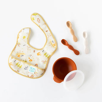 Bumkins Silicone Dipping Spoons 3 Pack: Rocky Road, a bowl with a transparent lid, and a colorful bib are arranged on a white background.