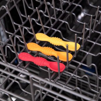 Bumkins Silicone Dipping Spoons 3 Pack: Tutti-Frutti sits in the top rack of an open dishwasher.