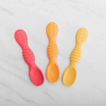 Bumkins Silicone Dipping Spoons 3 Pack: Tutti-Frutti lie on a white marble background.