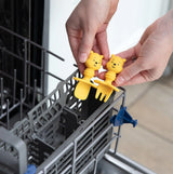 Hands place Bumkins Silicone Chewtensils®: Winnie The Pooh into the utensil compartment of an open dishwasher.