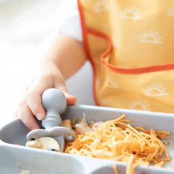 Close-up of a child's hand using a Bumkins Silicone Chewtensils®: Gray to eat spaghetti from a gray divided plate.