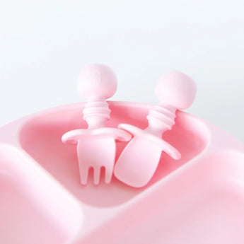 Close-up of Bumkins Silicone Chewtensils®: Pink in an empty section of a pink divided plate on a white background.