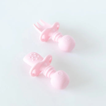 Bumkins Silicone Chewtensils®: Pink rest on a white background; one lays face down, displaying sensory bumps on the back.