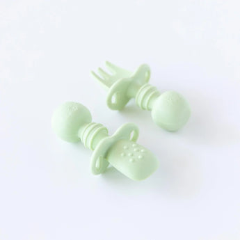 Bumkins Silicone Chewtensils®: Sage rests on a white background; one lays face-down, showcasing the sensory bumps on the back.