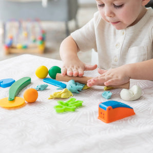 A child joyfully molds colorful clay on a Bumkins Splat Mat: Wander at a table.